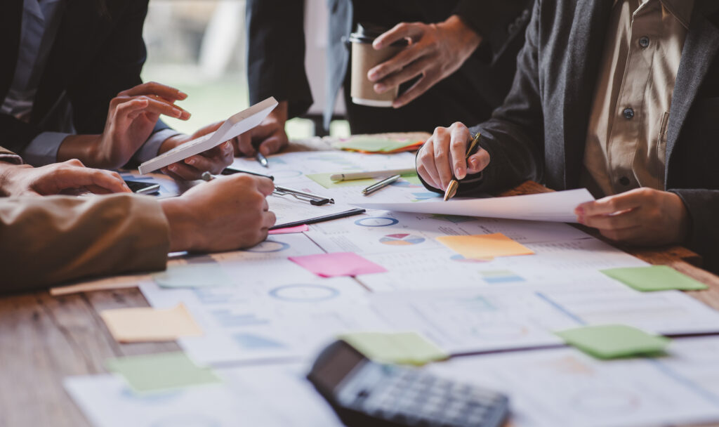 A group of business professionals gathered around a table, analyzing graphs and charts