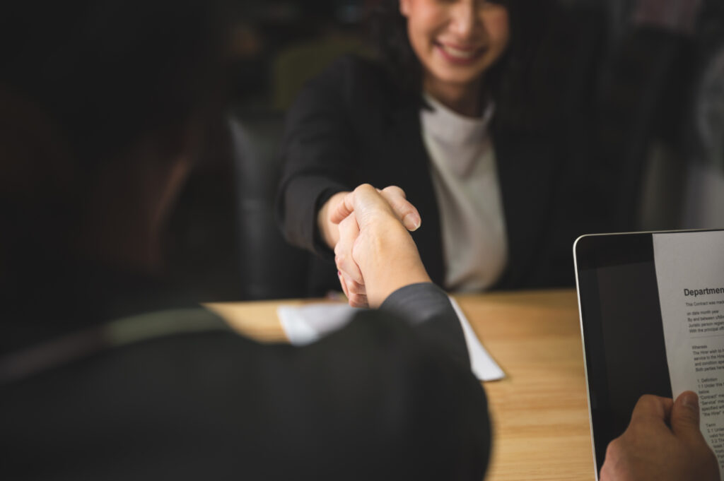 A smiling young professional shaking hands with a job interviewer