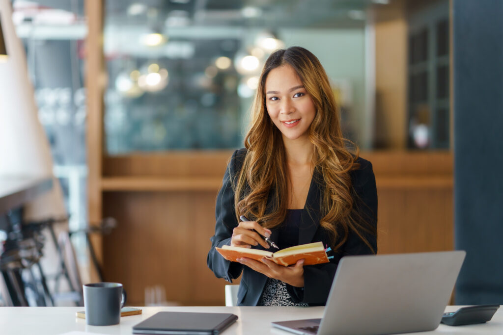 A young professional holding a pen and notebook in a cozy office environment